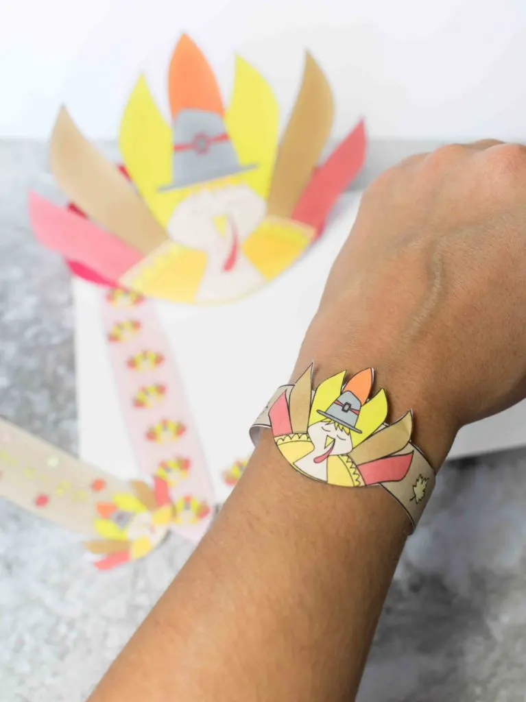 turkey bracelet craft wrapped around arm, with printables in the background