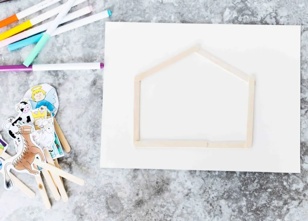 Nativity Scene house built out of popsicle sticks on a white card board stock paper