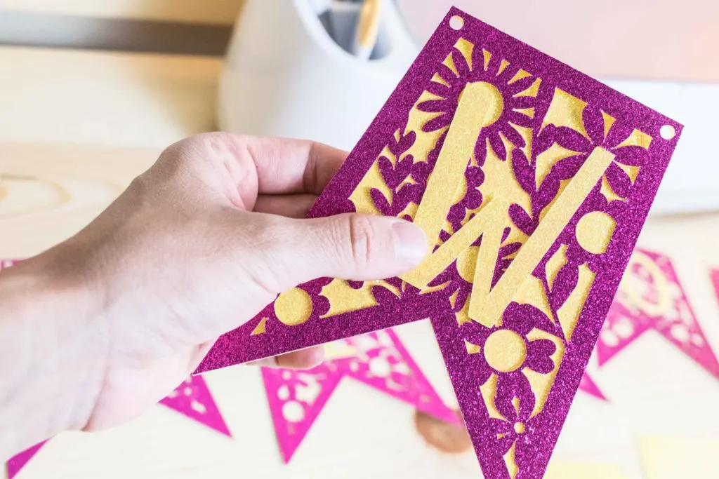 Holding a pink and yellow cut out banner made with Cricut.