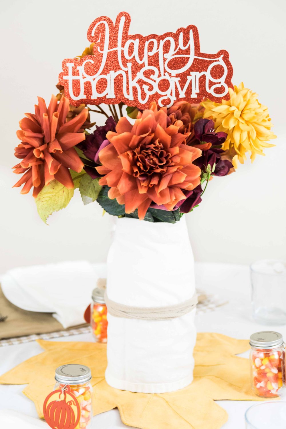 Vase with artificial fall flowers and a happy thanksgiving sign