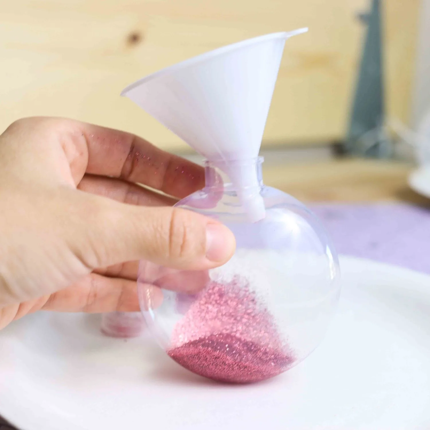 Using a funnel to add glitter to Christmas Ornaments