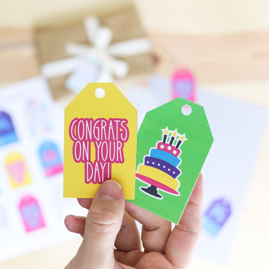 Holding two gift tags that say congrats on your day. 