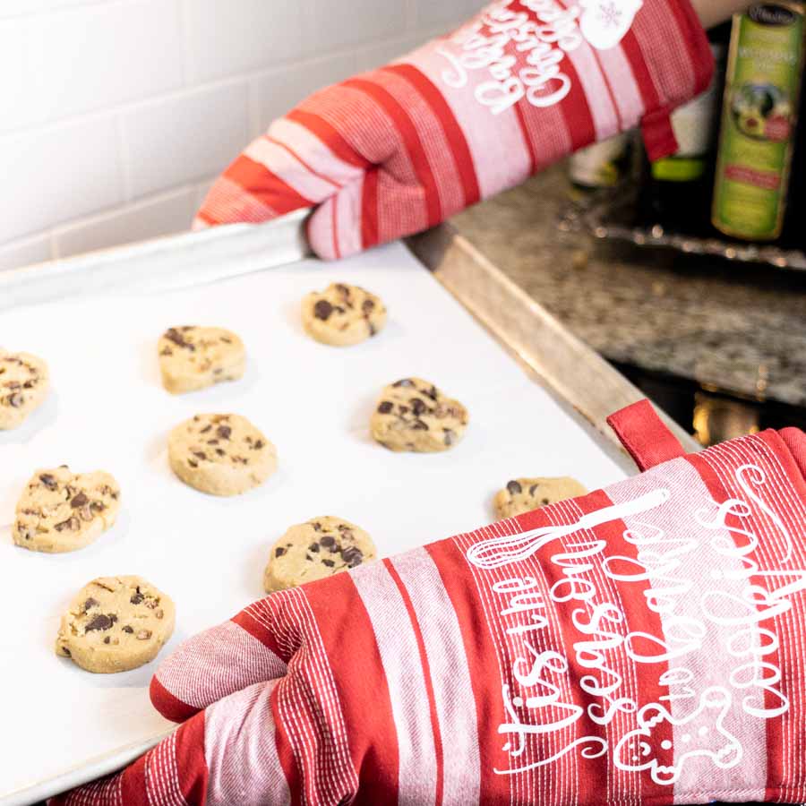 holding a baking cooking tray customized with cricut Christmas oven mittens