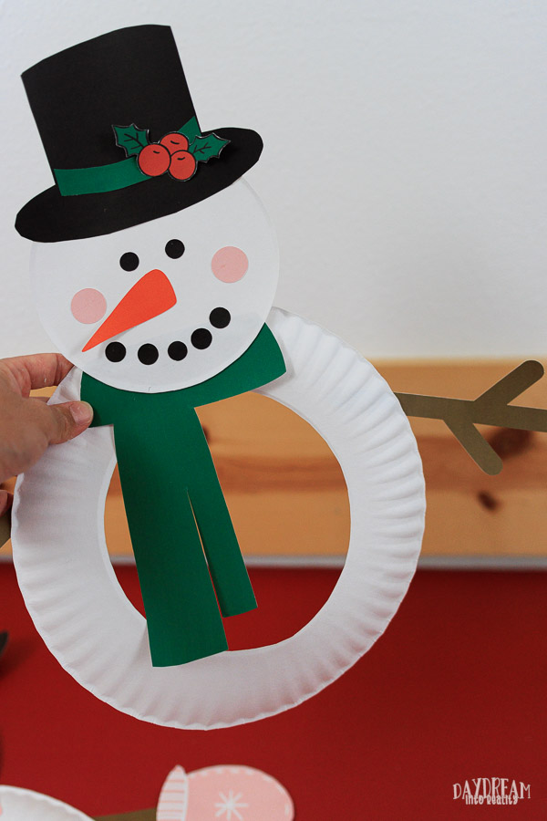 snowman paper plate craft for kids with hat and holly decoration, scarf