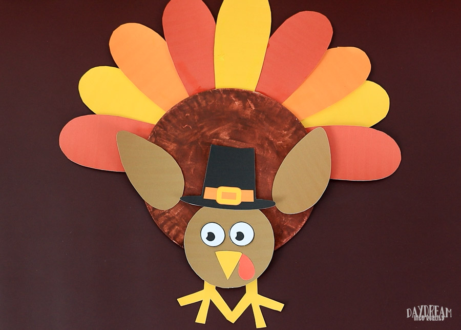 cute turkey craft for kids with pilgrim hat and looking down.