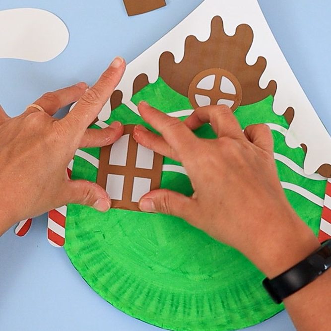 gluing windows on paper plate gingerbread house