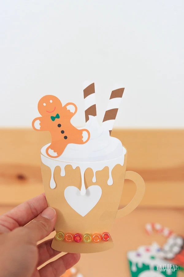 paper hot cocoa craft for kids - cream mug with beads, gingerbread man cookie, wafer straws and whipped cream.