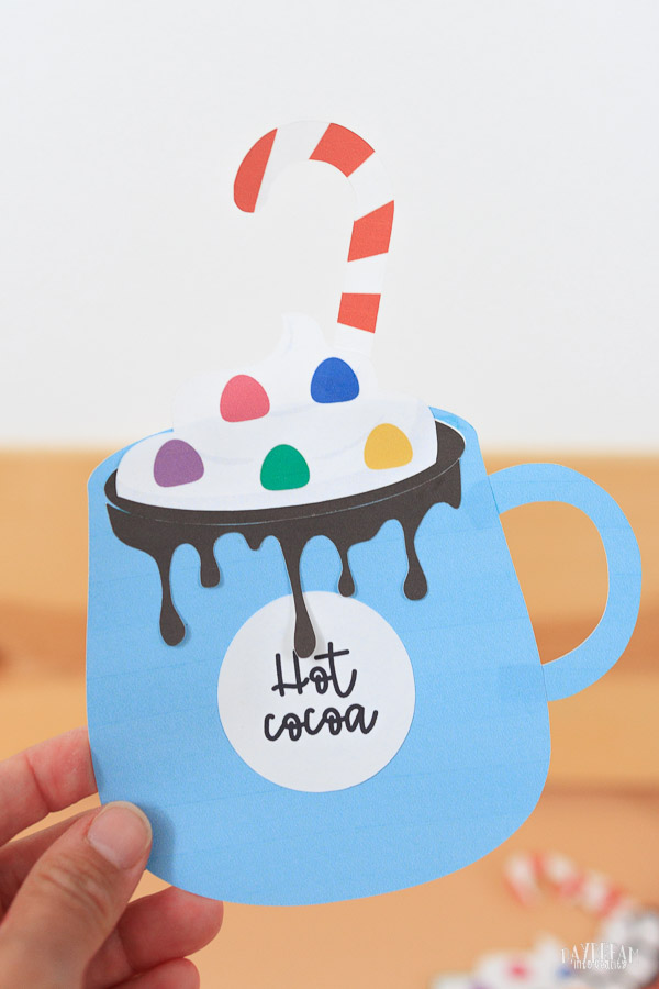 paper hot cocoa craft for kids - blue mug with whipped cream, sprinkles, and candy cane.