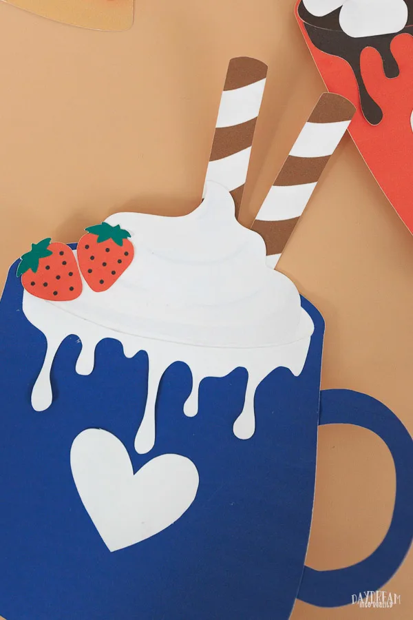 paper hot cocoa craft for kids - navy blue mug with wafer straws, whipped cream, dripping white chocolate and strawberries.